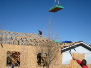 Roof sheathing is lifted by crane operator