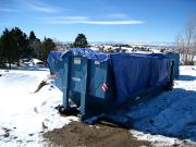 Dumpster is covered with tarp to keep trash from flying