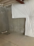 Insulation being installed over concrete walls in unfinished lower level